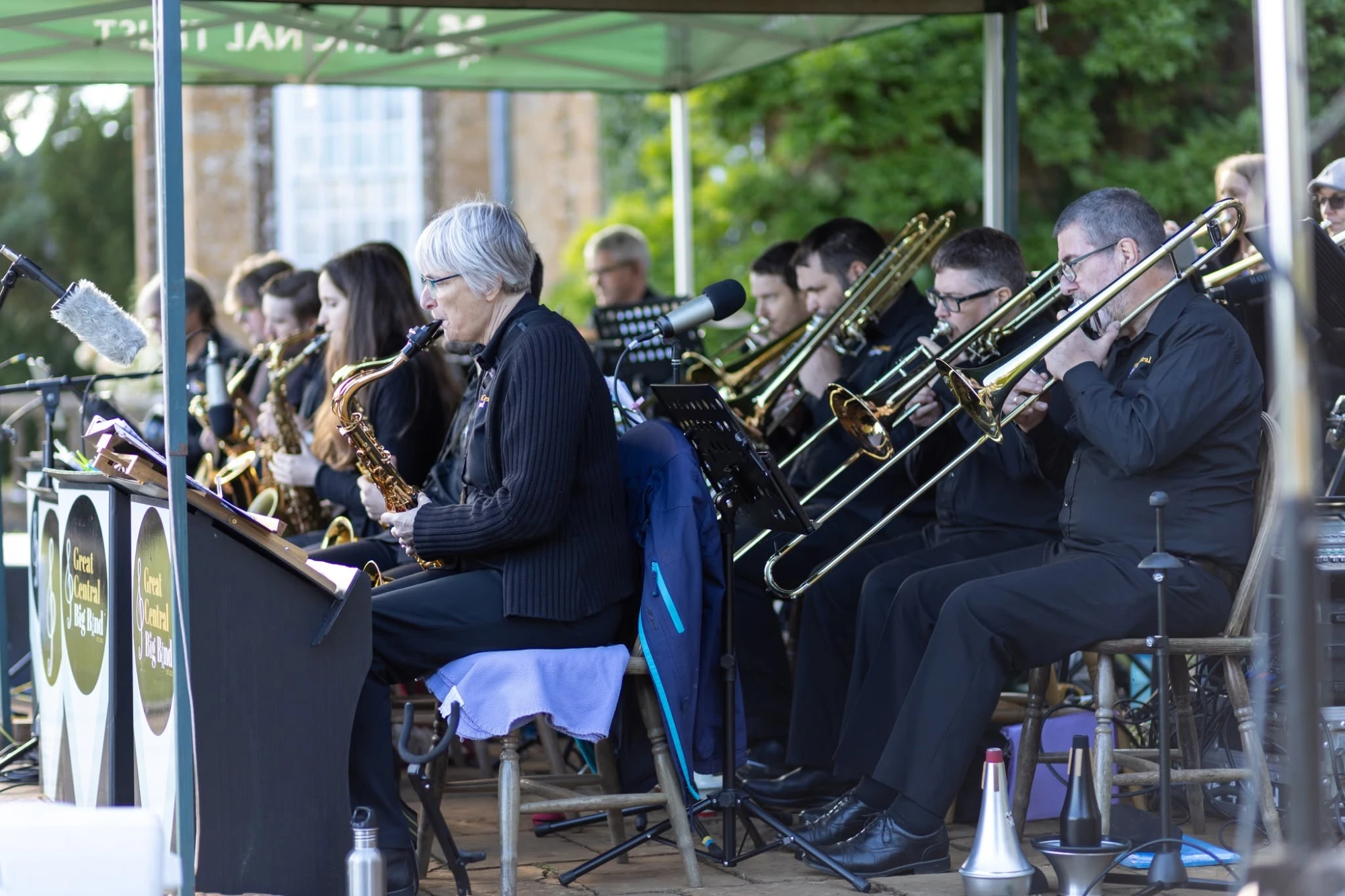 The saxophones and trombones playing outdoors under a National Trust gazebo, Great Central Big Band music stands in front